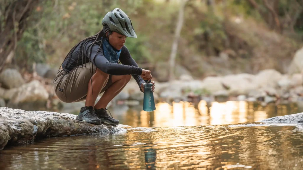 Person collecting drinking water from a river using a portable water filter.
