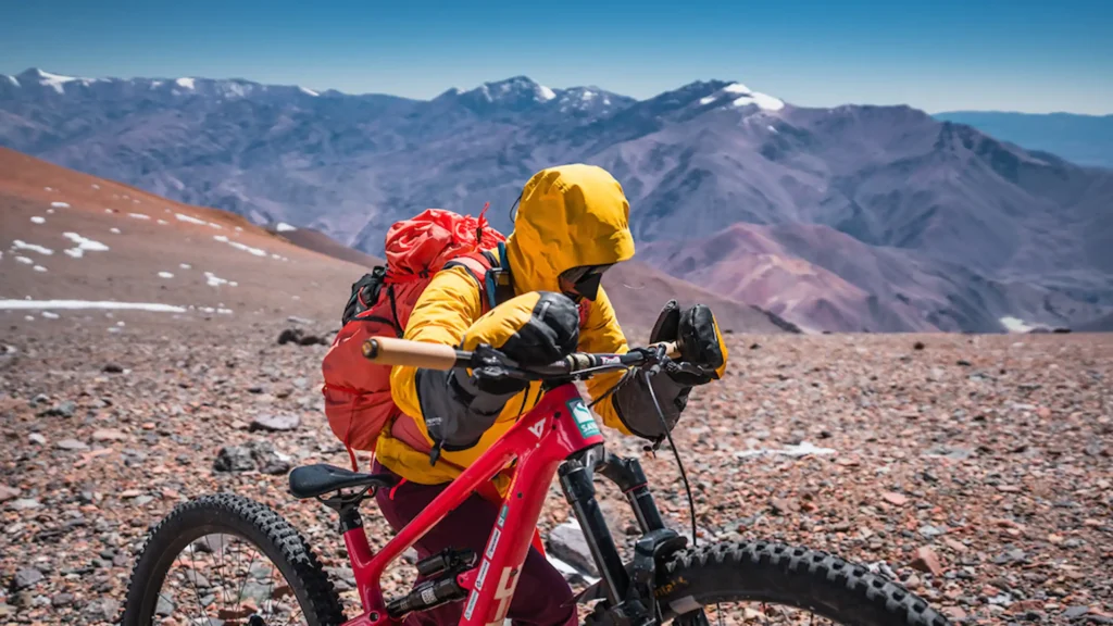 Rea Kolbl pushing a mountain bike at high altitude during the Cerro Mercedario expedition